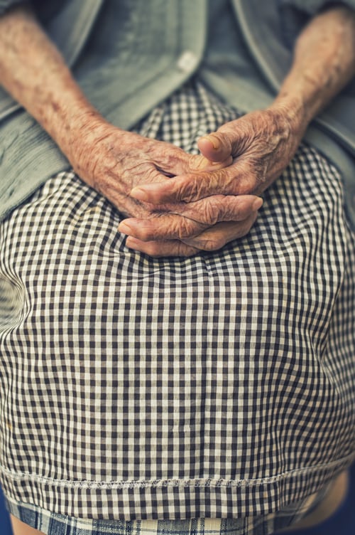 Hands of an older woman folded in her lap
